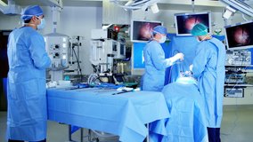 Laparoscopic surgical operation transmitted on hospital monitor performed by Caucasian males training as surgeons wearing gloves and scrubs RED DRAGON