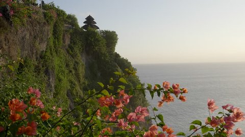 late afternoon shot of bali's uluwatu temple with bougainvillea flowers in the foreground