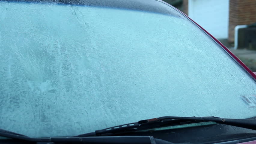 Scraping off the ice on a car's windshield on a cold Winter morning.