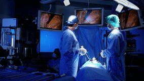 Laparoscopy surgical operation transmitted on hospital monitors performed by female African American and Caucasian male training as surgeons wearing surgical mesh and scrubs RED DRAGON