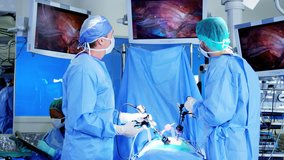 Professional Multi ethnic hospital specialist team in scrubs in the operating theatre performing Laparoscopy surgery using video monitor playback and Endoscope and Laparoscope instruments RED DRAGON