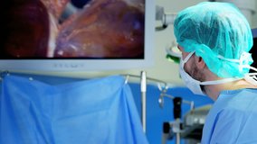 Laparoscopy surgical training operation transmitted on hospital monitors performed by male Caucasian wearing surgical gloves and scrubs RED DRAGON