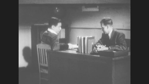 1950s: Boy talks to man while sitting at desk. He stands, then walks to different desk. Man speaks, then opens file that says "the pros and cons of world federation."