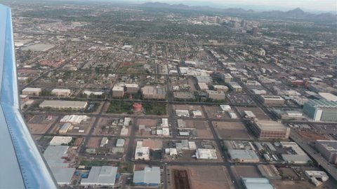 Aerial airline approach Phoenix Arizona down town urban area. View from inside along the wing to the ground. Urban city business, residential and agricultural land. Vacation and business travel. 