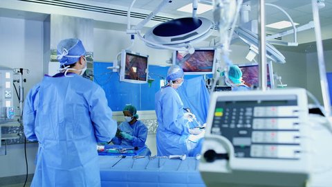 Surgical hospital Laparoscopic medical Operation carried out by Caucasian male and female specialist team in scrubs and African American Anesthesiologist RED WEAPON