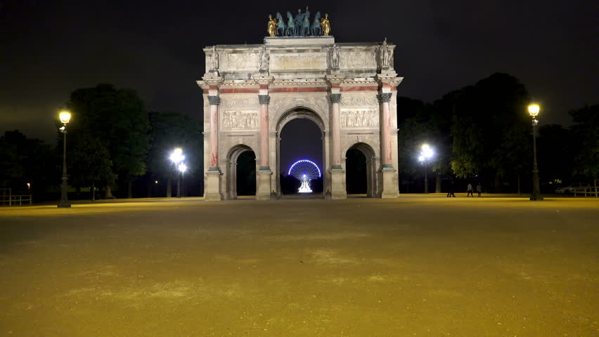 Arc de Triomphe du Carrousel in Paris at  night with view of Eiffel tower lights and Ferris Wheeel at backoorund