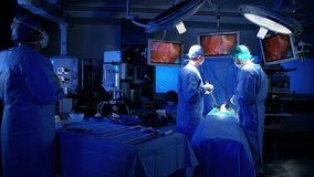 Multi ethnic European Caucasian surgical team in scrubs performing Laparoscopy surgery on the patient in operating theatre using video camera playback technology RED DRAGON