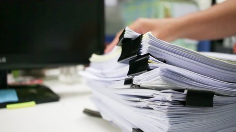 Businessman hands searching information in Stacks of paper files on work desk office, business report papers or piles of unfinished documents achieves with clips on offices indoor, Business concept