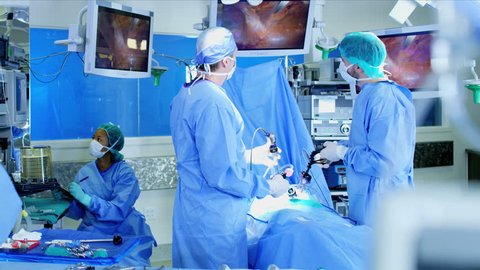 Surgical hospital Laparoscopic Operation carried out by Caucasian male and female specialist team in scrubs and African American Anesthesiologist RED WEAPON