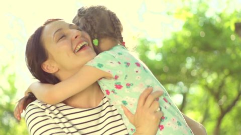 Beautiful Mother And her little daughter outdoors. Nature. Beauty Mum and her Child playing in Park together. Kissing and hugging happy family. Happy Mother's Day Joy. Mom and Baby. Slow motion 4K UHD