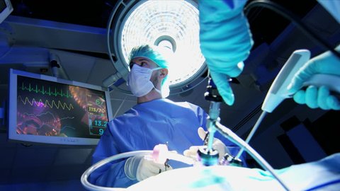 Medical European Caucasian surgical team in scrubs training performing laparoscopic surgery on the patient in sterile operating theater using video camera technology RED WEAPON