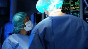 Laparoscopy surgical operation transmitted on hospital monitors being performed by multi ethnic female training as surgeon wearing surgical gloves and scrubs RED DRAGON