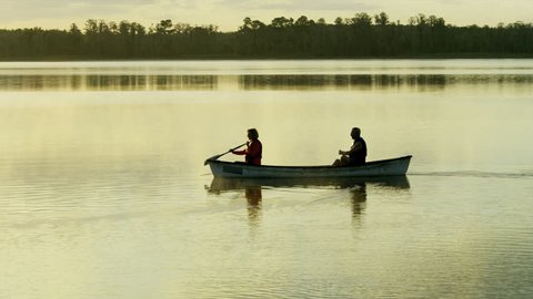 Mature Caucasian American senior couple enjoying their outdoor lifestyle at sunrise canoeing on the vacation resort lake RED WEAPON