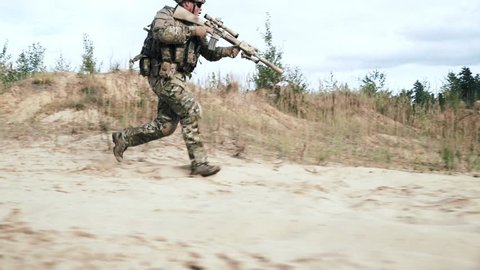 Military soldier with sniper rifle running on sand side view. Military soldier with weapon running on sand sand