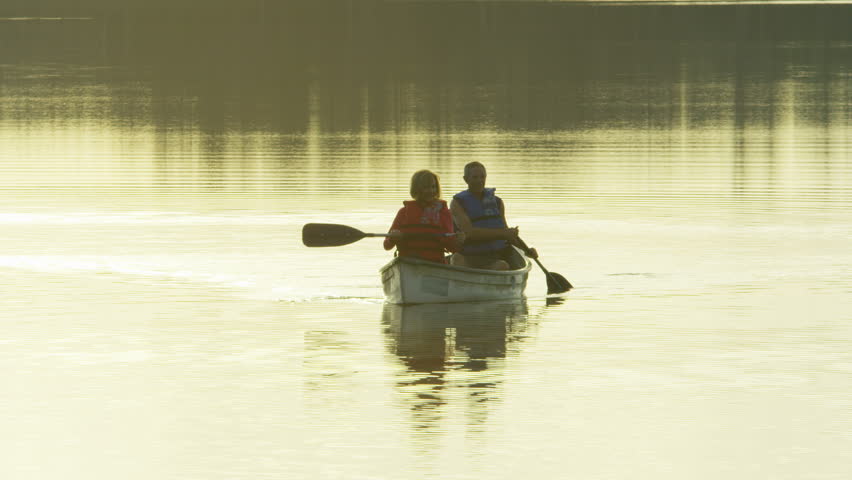 Mature Caucasian European couple in the canoe on the lake paddling and enjoying the sunset RED WEAPON