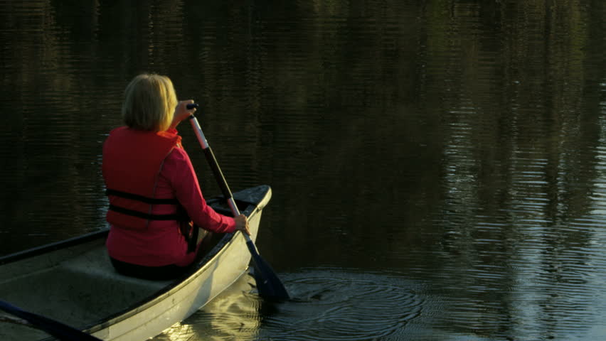 Active senior Caucasian American couple outdoors in the canoe on the lake paddling and enjoying the sunrise RED WEAPON