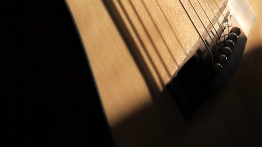 Acoustic Guitar Tilting Up. An acoustic guitar resting against a wall in warm