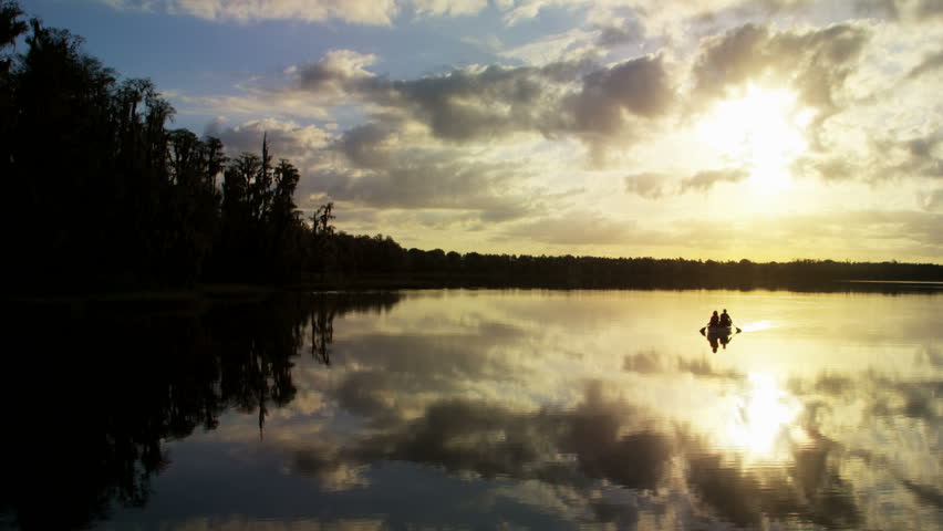 Silhouette of mature Caucasian American couple in the boat on the lake paddling and enjoying the sunrise RED DRAGON