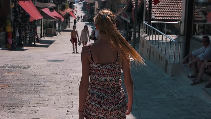a girl walks down the street with paving stones.