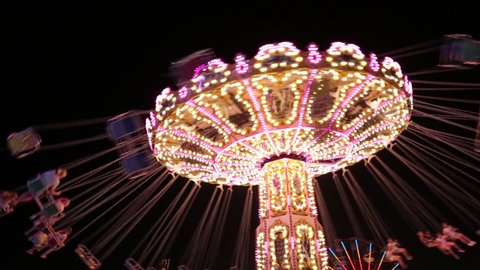 Popular Chair Swing Rides in Amusement Park. Carousel with lights. Night shooting. Looped. Festive fun at the fair