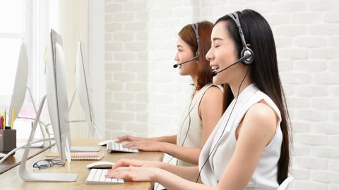 Smiling Asian telemarketing customer service agent team working in the office, call center job concept