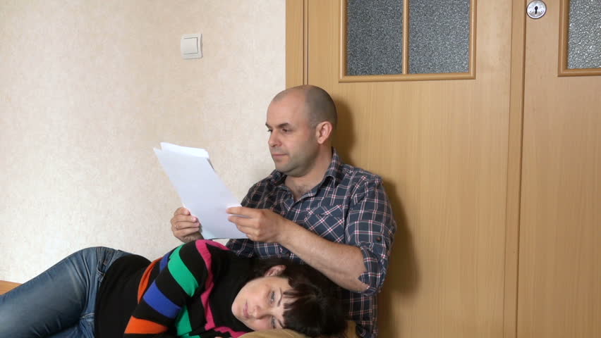 Husband are looking at unpaid bills. Sad married couple sitting on the floor. Peopls is bankrupt. 