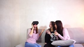 Attractive girls hold modern devices, VR glasses and inspect, study possibilities of gadget and communicate with each other. One of female friends put on VR glasses on head and plunged into parallel