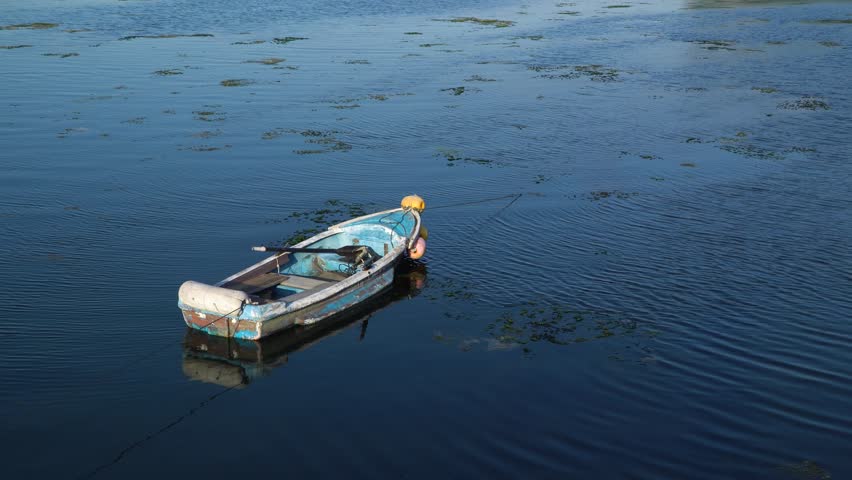 Betied old blue boat with a paddle on a shallow seaside in Ozo-ri, Jeju, Korea.