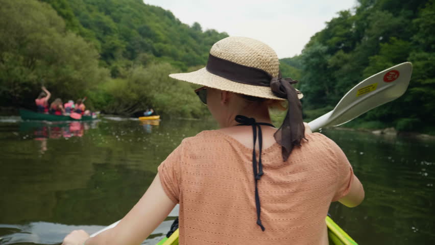 Young girl canoeing with a group of canoes in a beautiful lake on sunny water in 4k