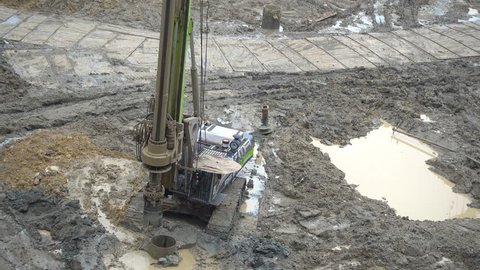 Tractor with drilling device, drilling soil on ground at construction site and found water flooding, top view 
