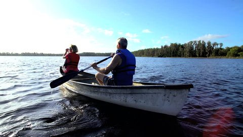 Healthy Caucasian American seniors wearing lifejackets enjoying their outdoor leisure kayaking on the lake Stock video