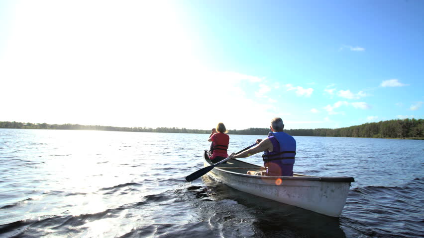 Retired Caucasian American couple wearing lifejackets enjoying their vacation having kayaking trip on the lake outdoors