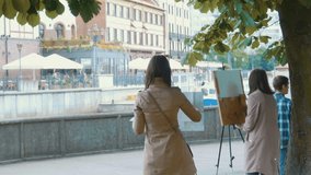 Young artists draw in the city park. Artists painting picture on the street. Students paint the urban landscape of the old European city.