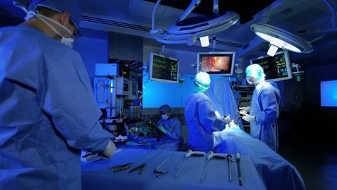 Laparoscopic medical surgical operation transmitted on hospital monitors performed by Caucasian hospital surgeons wearing gloves and scrubs RED WEAPON