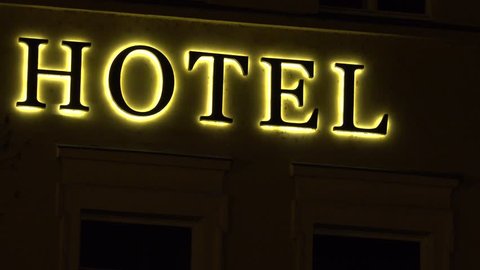 Closeup on a yellow and black neon hotel sign at night