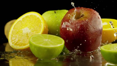 fresh fruits splashed by water in slow motion