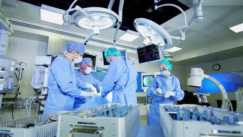 Surgical healthcare medical training team in scrubs working in modern hospital operating theater facility performing Orthopaedic surgery on patient RED WEAPON Arkivvideo