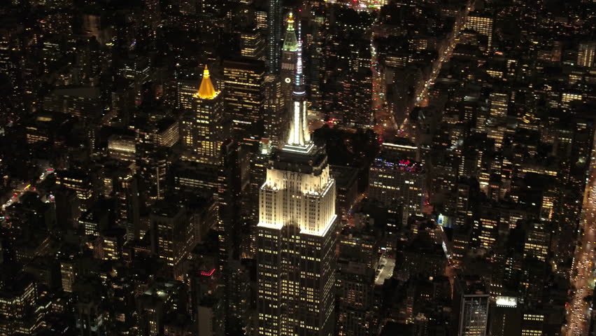 NEW YORK USA - SEPTEMBER 4, 2016,AERIAL HELI SHOT: Flying above the parallel streets under iconic Empire State Building shining lit up with lights on magical summer night in New York City. 