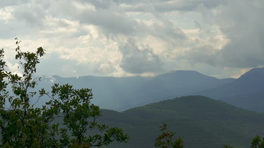 Storm clouds over blue mountains covered with forests, time lapse / Rain clouds over mountains, time lapse 