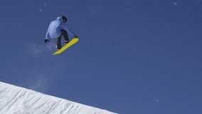 SLOW MOTION: Young pro snowboarder riding the half pipe in big mountain snow park, jumping out of the halfpipe wall and over the sun, performing tricks and rotations with grabs in sunny winter - Powered by Shutterstock - Get 15% off with code: PIKWIZARD15