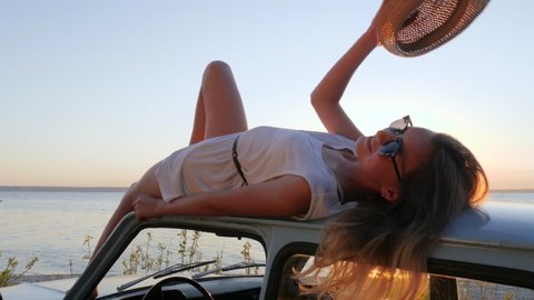 young woman relax at roof auto enjoying freedom outdoors at background sea in slow motion, summer travel