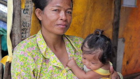 Mother feeding baby in Cambodian slums, close to dump area