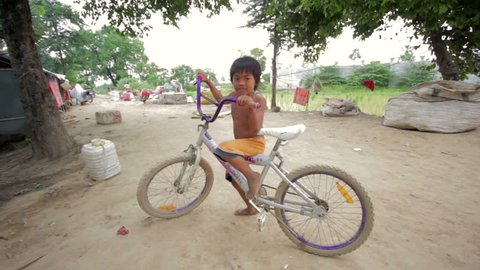 Cambodian boy in slum on bike Stock Video