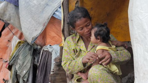 Mother feeding baby in Cambodian slums, close to dump area