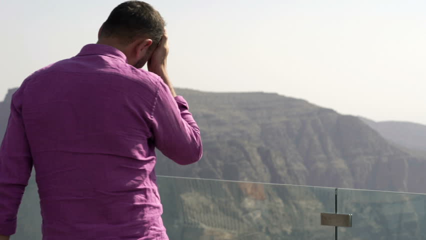 Unhappy, depressed man standing on terrace with canyon view
