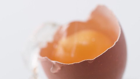 Breaking egg. Egg yolk falls into broken egg shell. Shot with high speed camera, phantom flex 4K. Slow Motion.