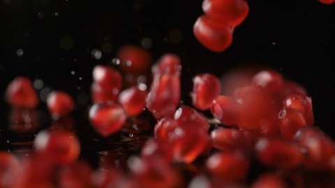 Pomegranate seeds falling on water surface. Shot with high speed camera, phantom flex 4K. Slow Motion.