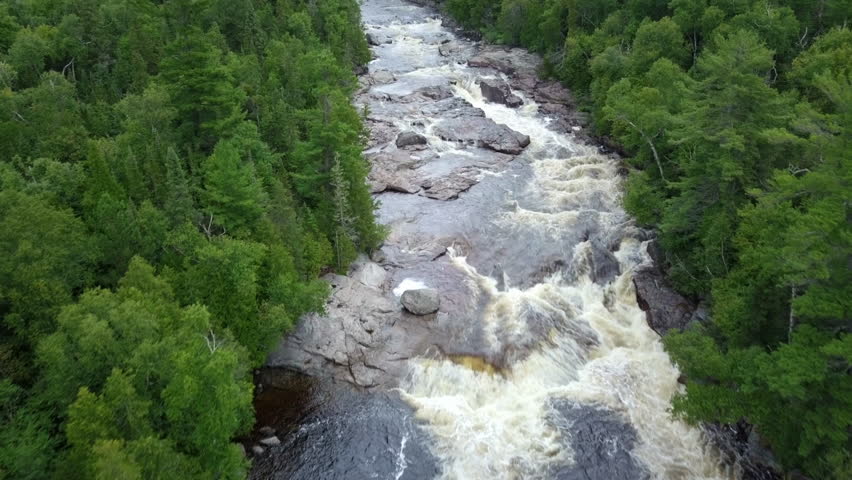 High angle aerial drone shot of raging river in a forest