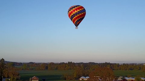 This is an aerial video of a hot air balloon flying far away.
