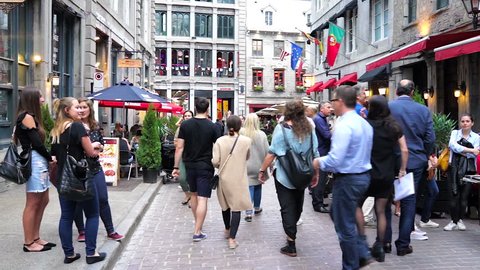 Montreal, Canada - May 27, 2017: Old town area with many crowd of people walking on street in evening by restaurants in Quebec region city